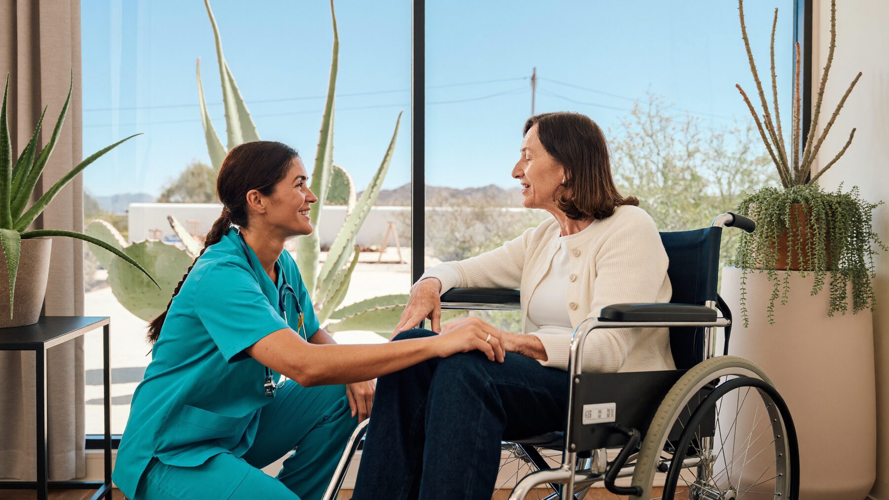 Nurse practitioner talking at eye level with a patient seated in a wheelchair.